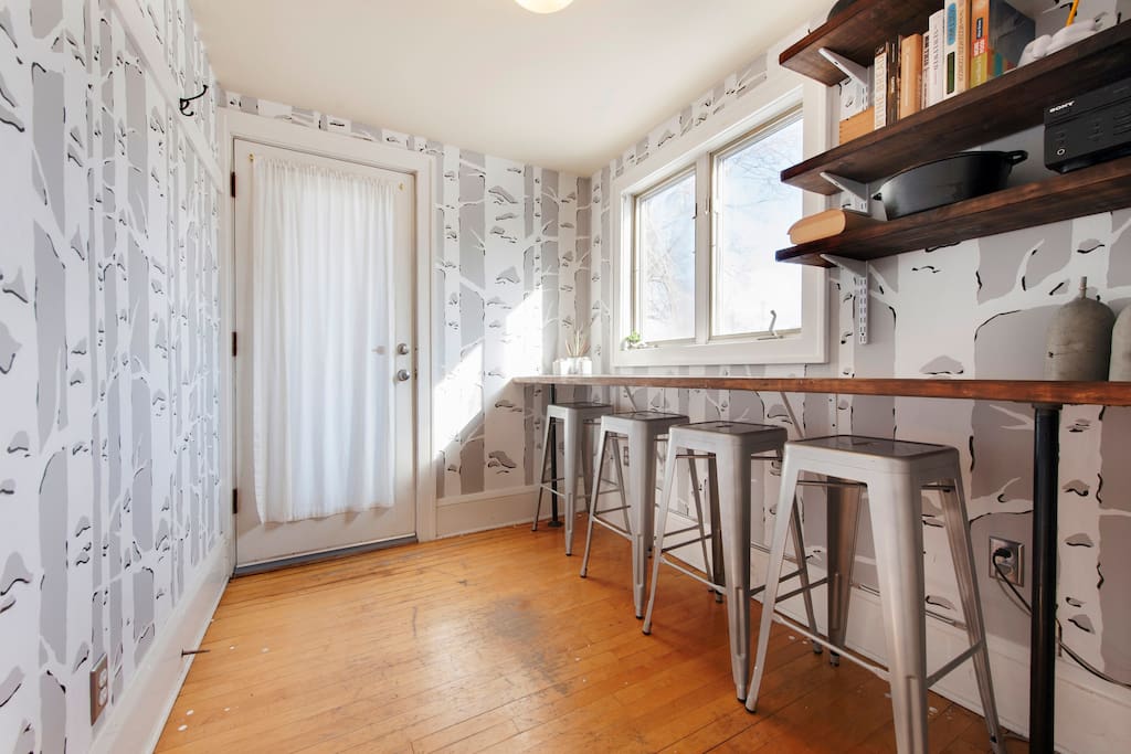 Dining nook with bird wallpaper, bar stools, and deck door